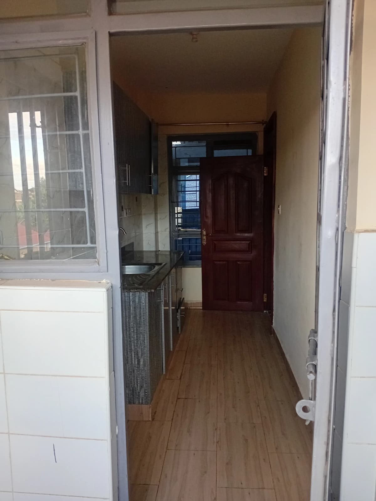 Narrow entrance hallway with wooden flooring and security gate