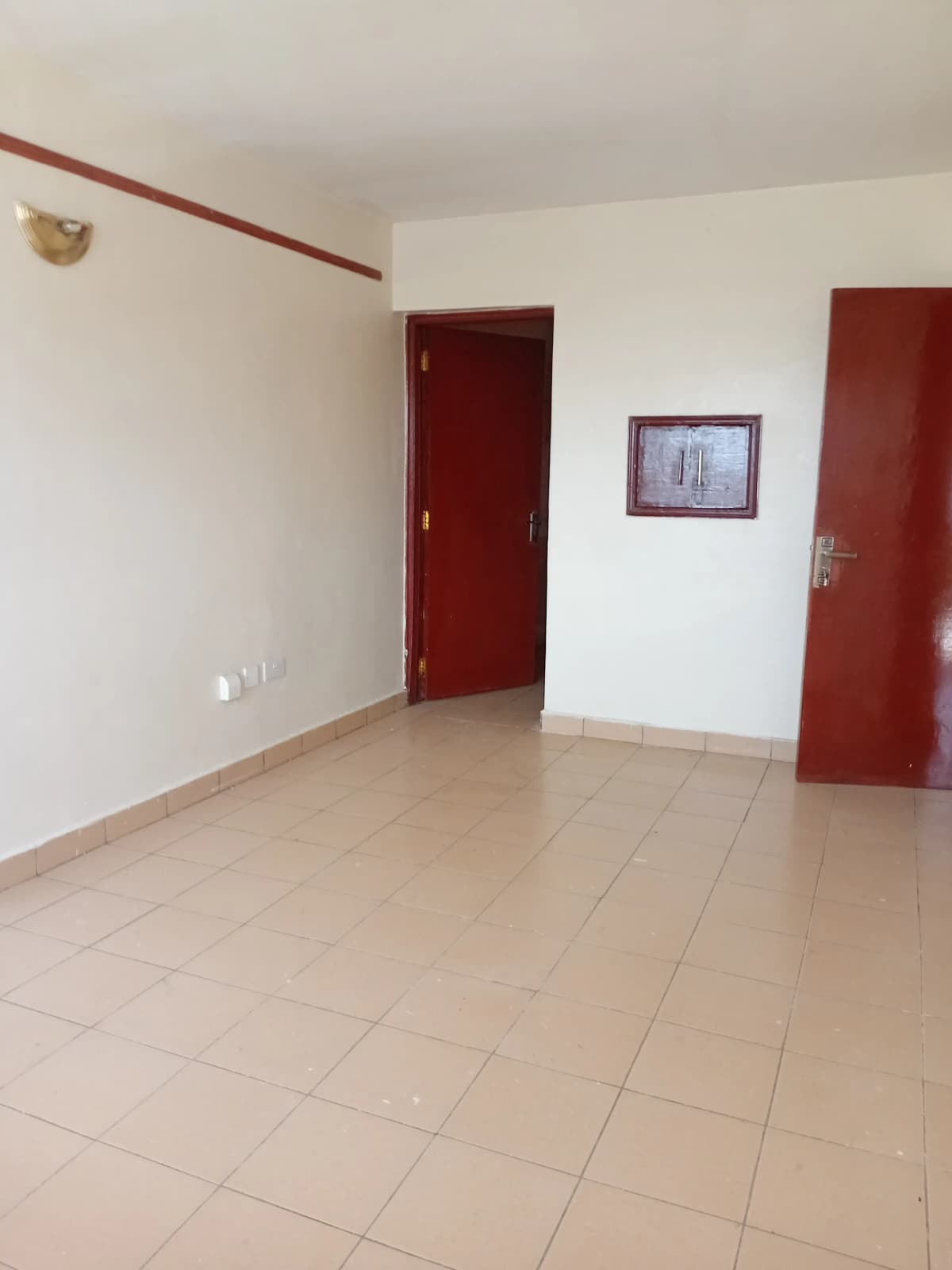 Spacious empty living area with tiled flooring and burgundy doors