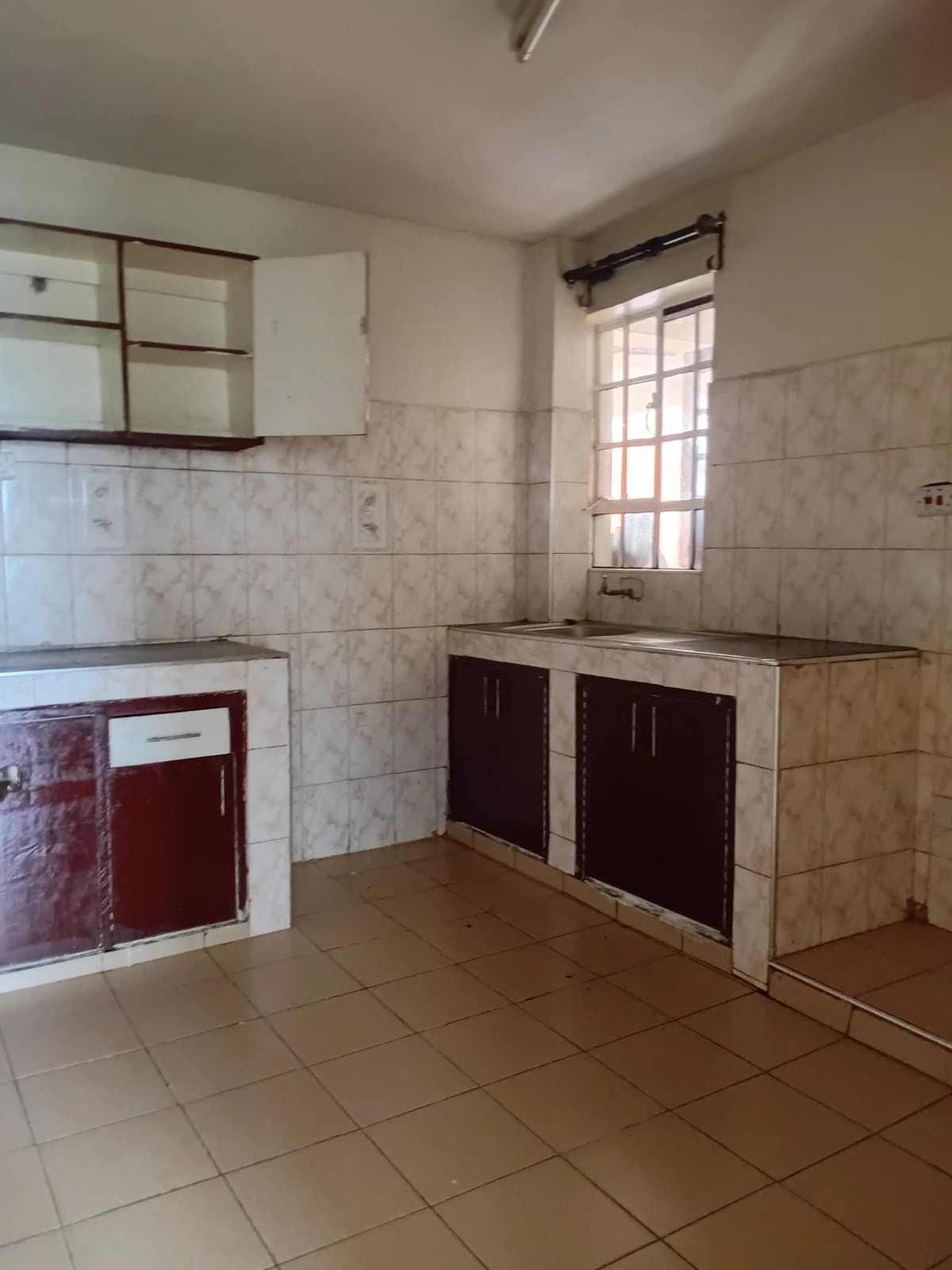 Spacious kitchen with dark red cabinets and tile backsplash