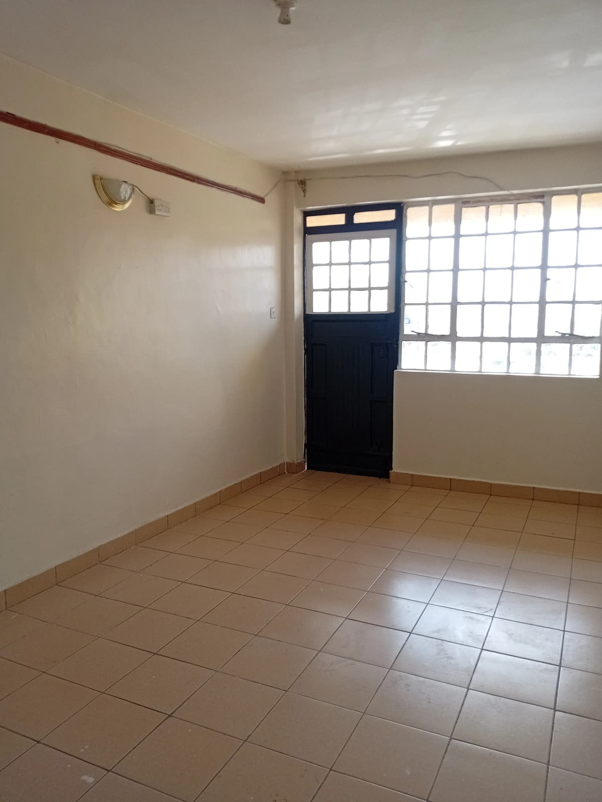 Bare bedroom with tiled floor and barred window door