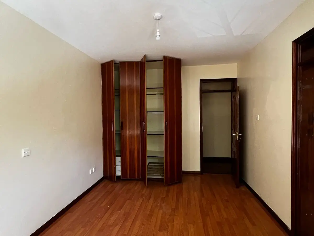 Spacious bedroom with wooden wardrobe and hardwood flooring