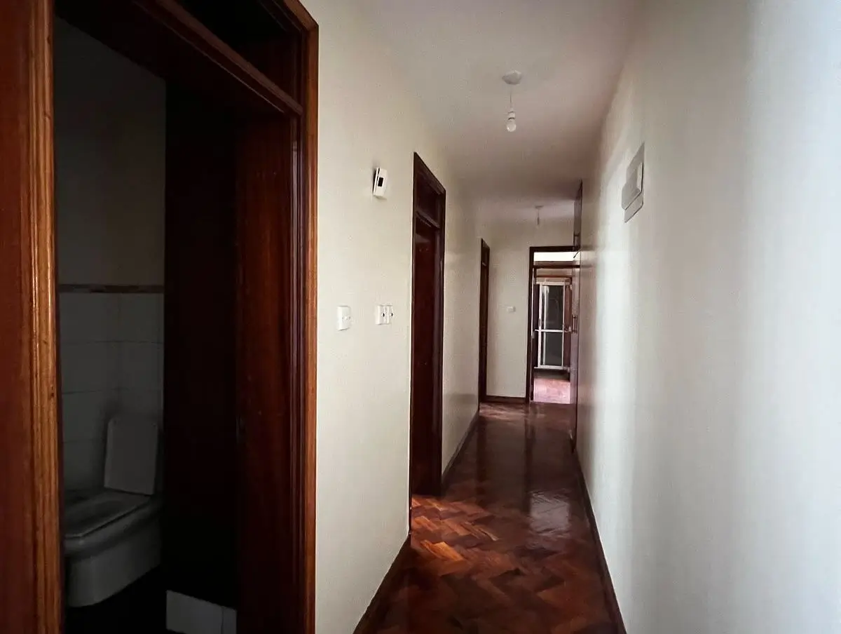 Long hallway with dark wood doors and terracotta flooring