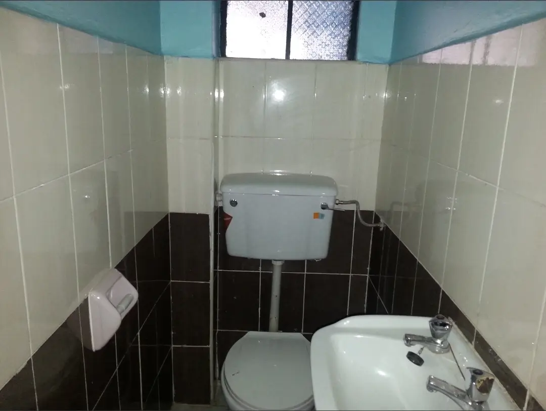 Compact bathroom with black and white tile, toilet and sink