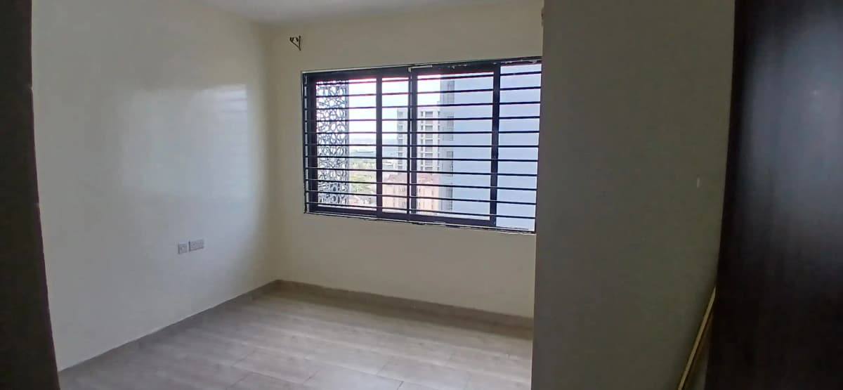 Bare bedroom with barred window and wooden flooring