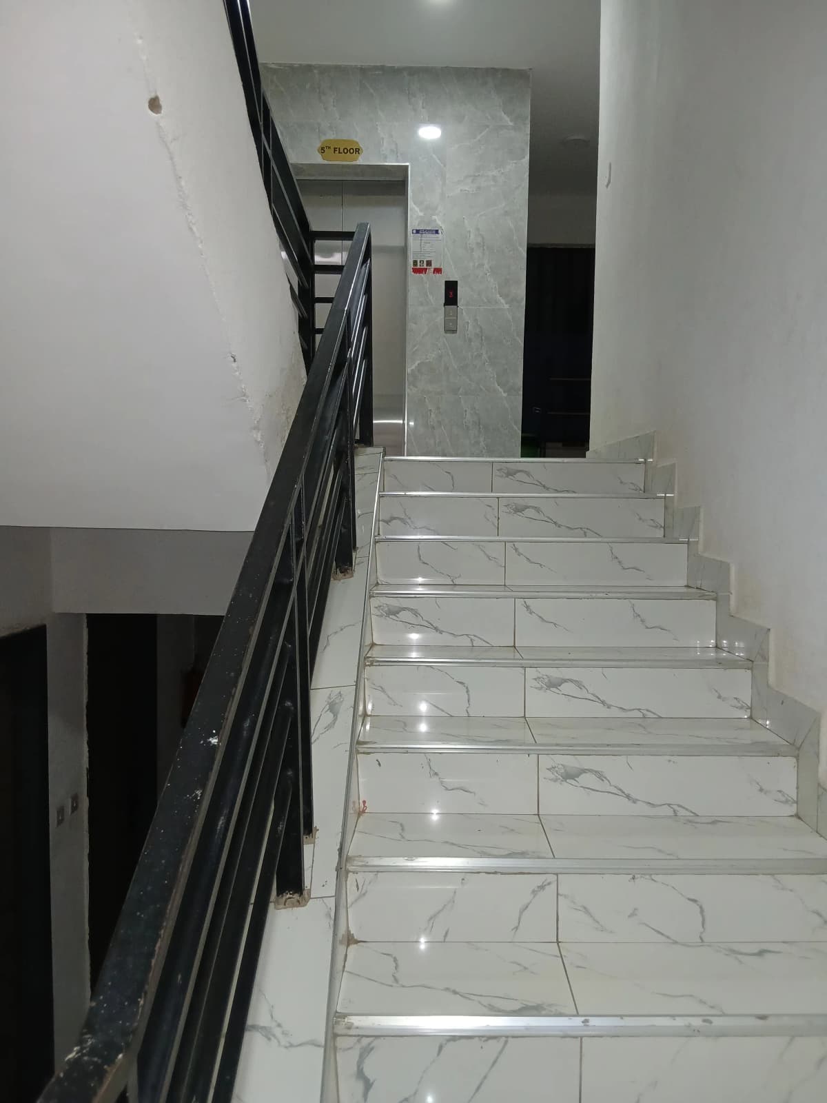 Modern staircase with marble tiles and black metal railing