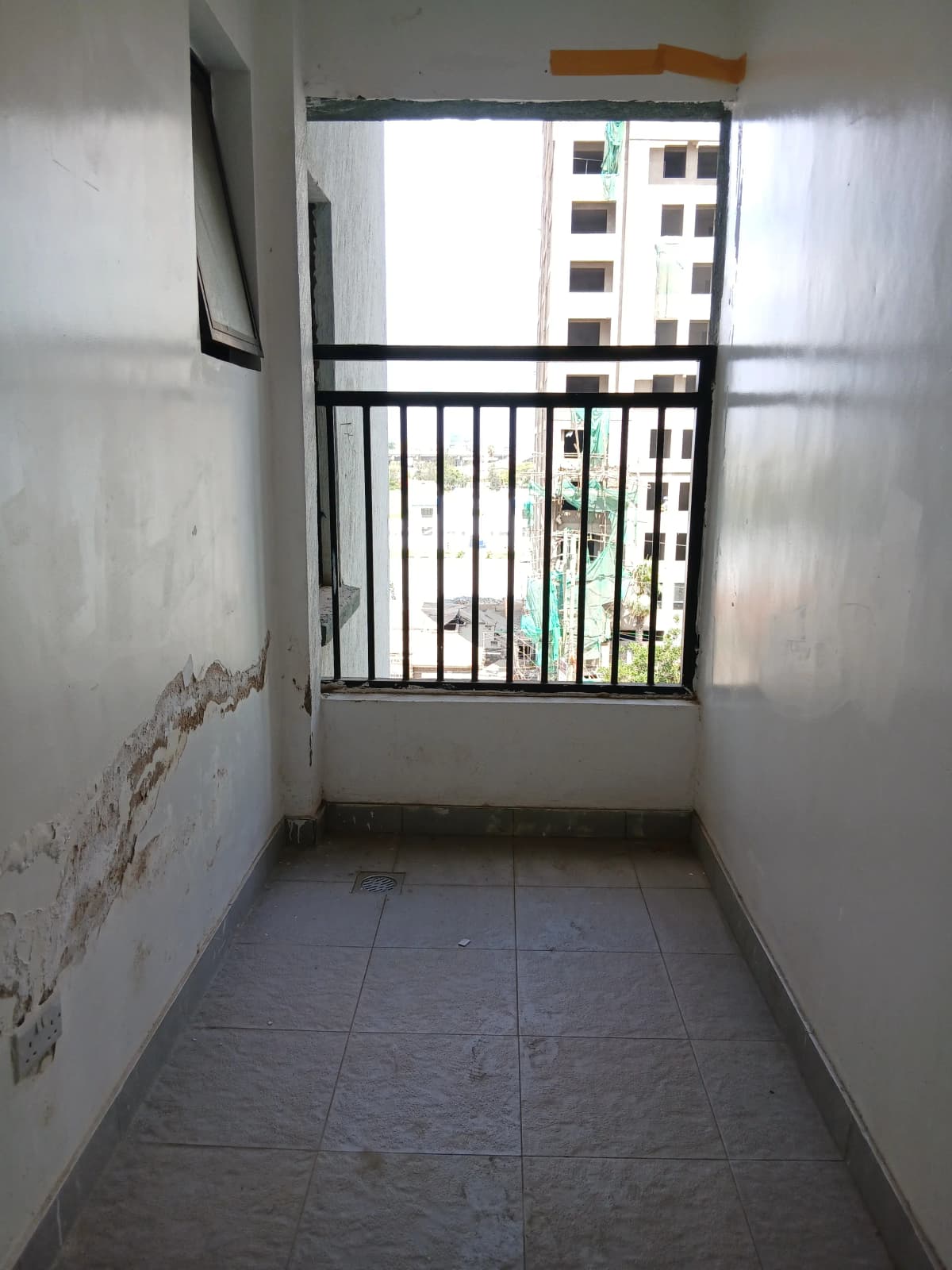 Narrow balcony with black railings overlooking residential buildings