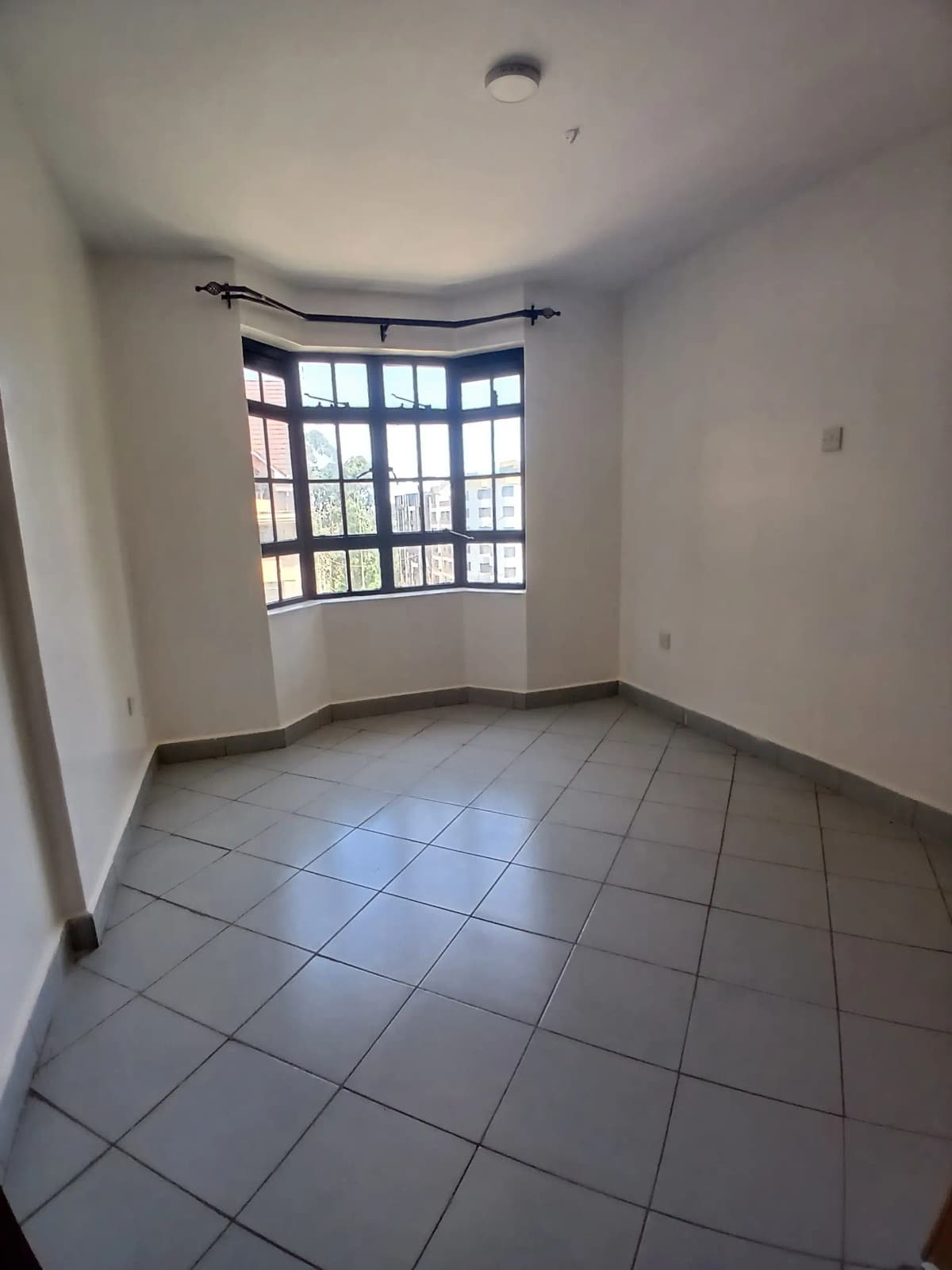 Bright bedroom with curved window wall and tiled flooring