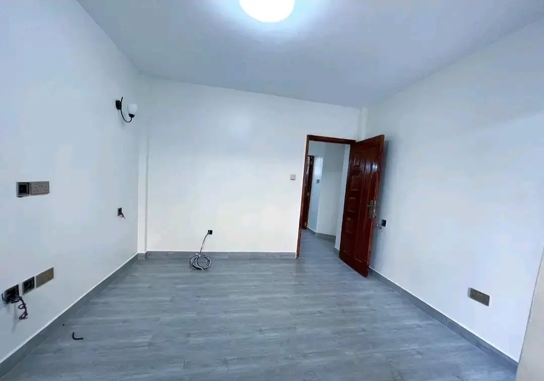 Spacious empty bedroom with grey flooring and red door
