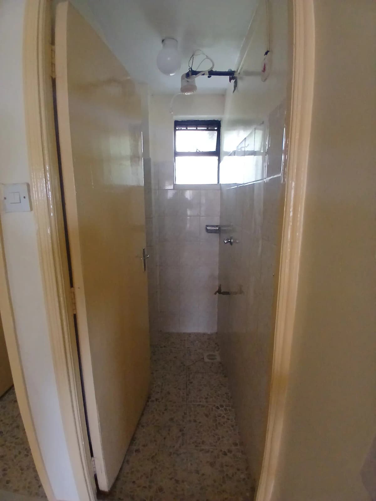 Narrow bathroom with shower enclosure and small window