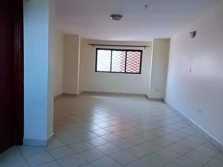 Spacious empty living room with tiled flooring and natural light