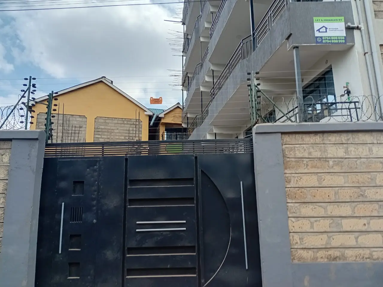 Compound entrance with black metal gate and perimeter walls