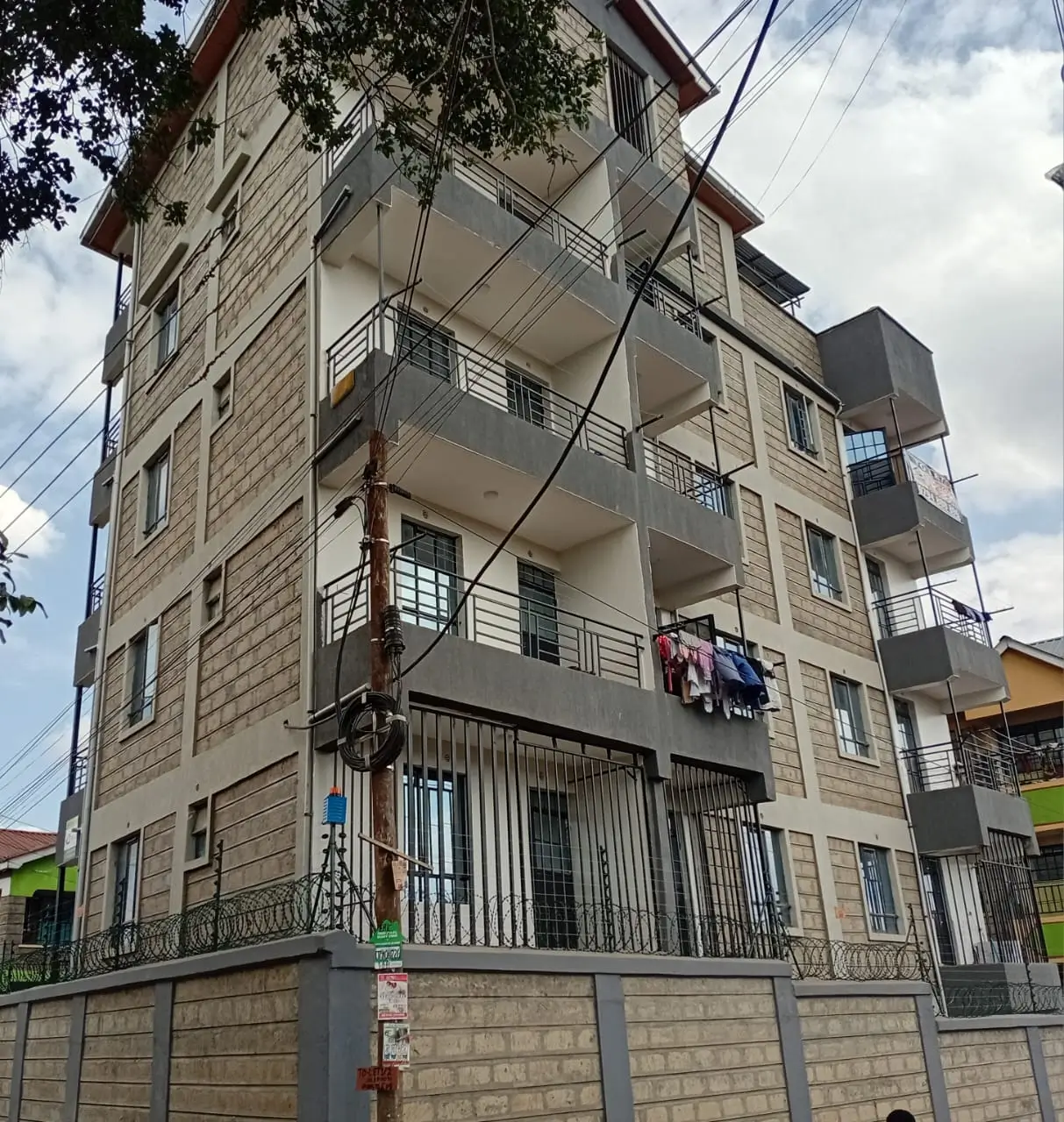 Multi-story residential building with balconies and ground-floor gates