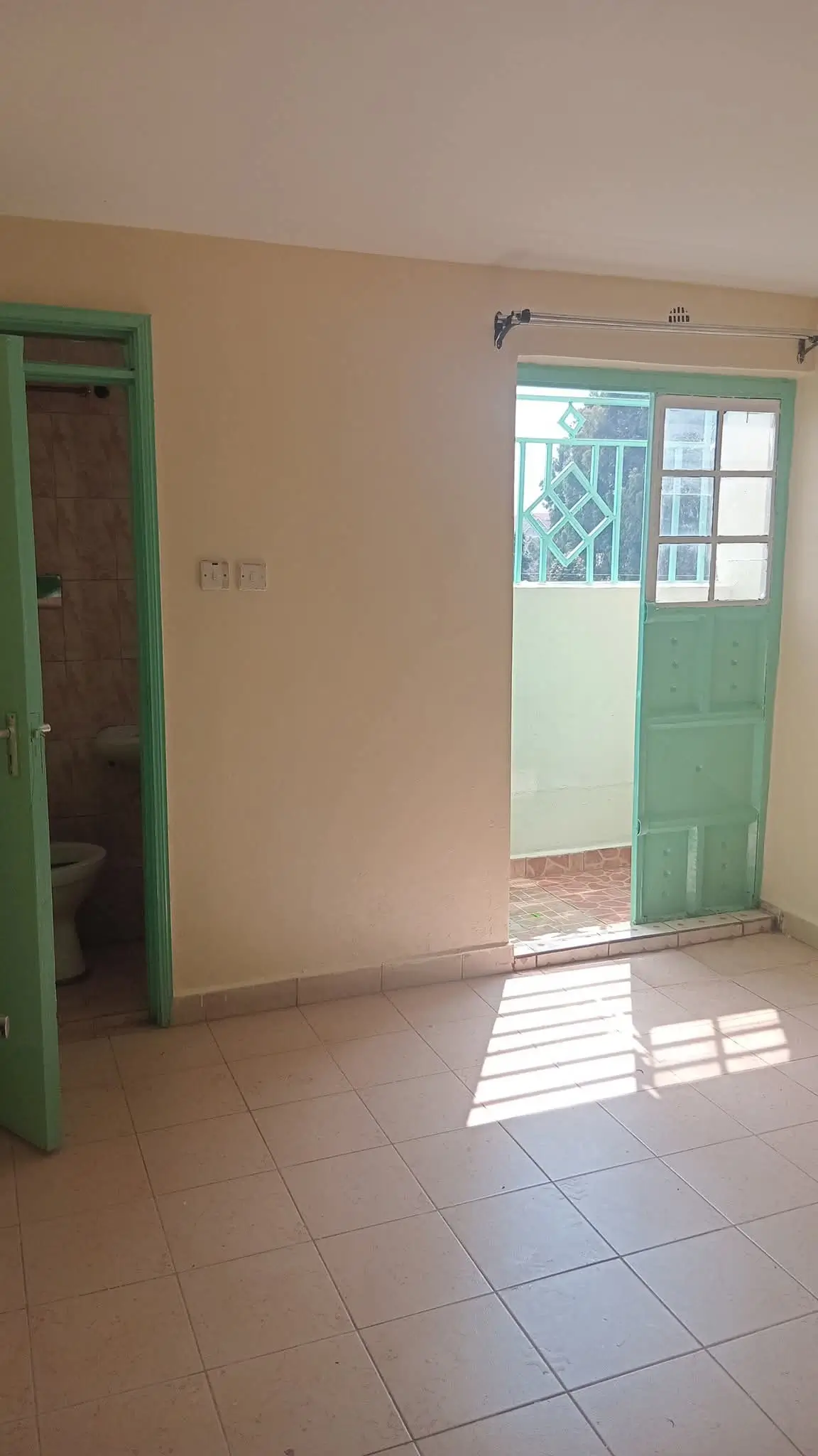 Bright empty living room with green doors and tiled floor