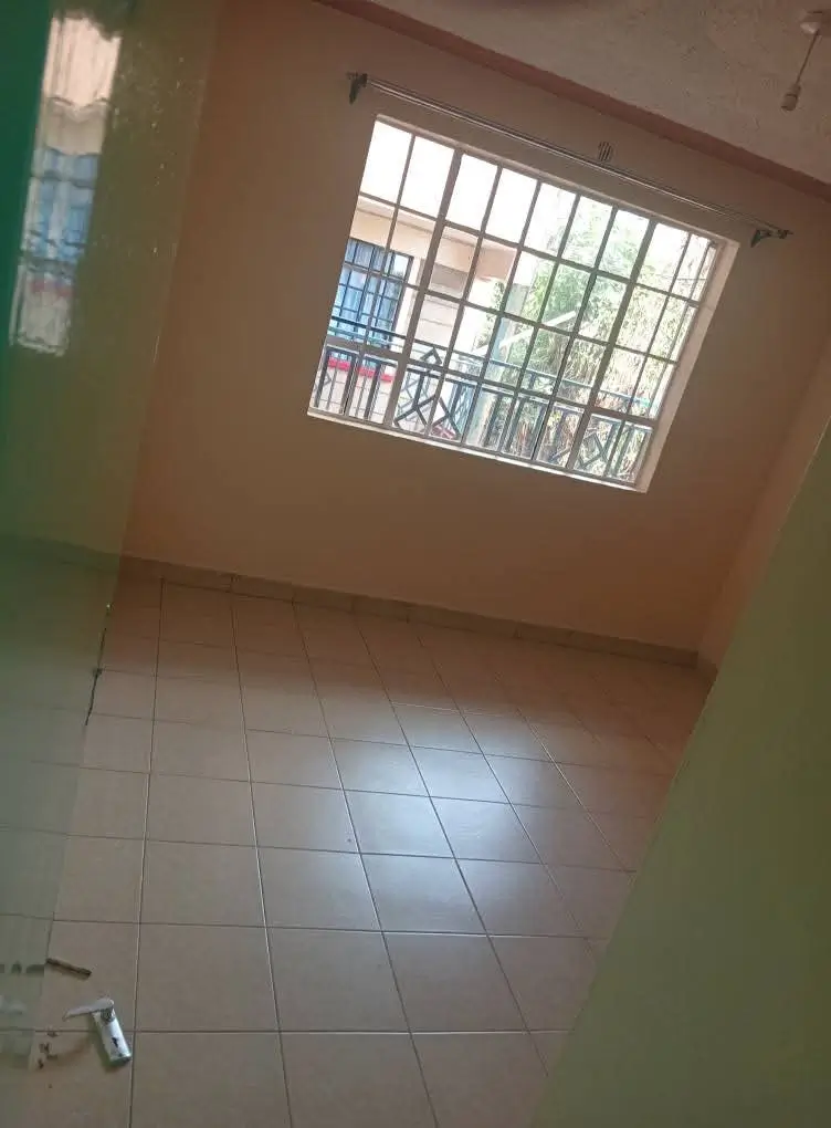 Sparse bedroom with tiled floor and barred window