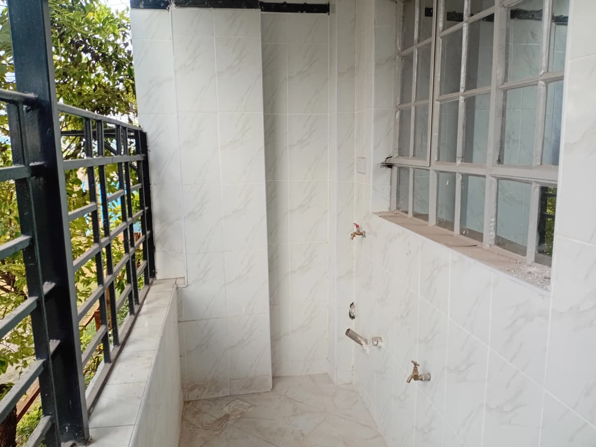 Covered balcony with black railing and garden views