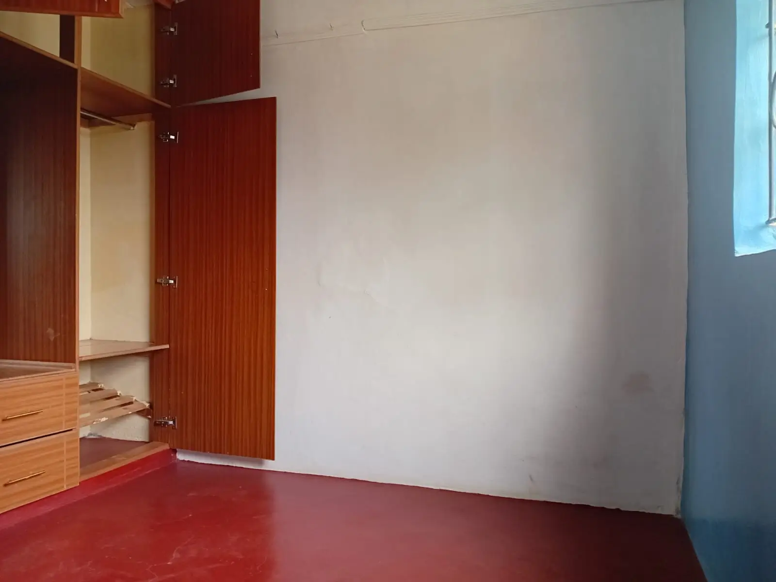 Minimalist bedroom with red polished floor and wooden wardrobe