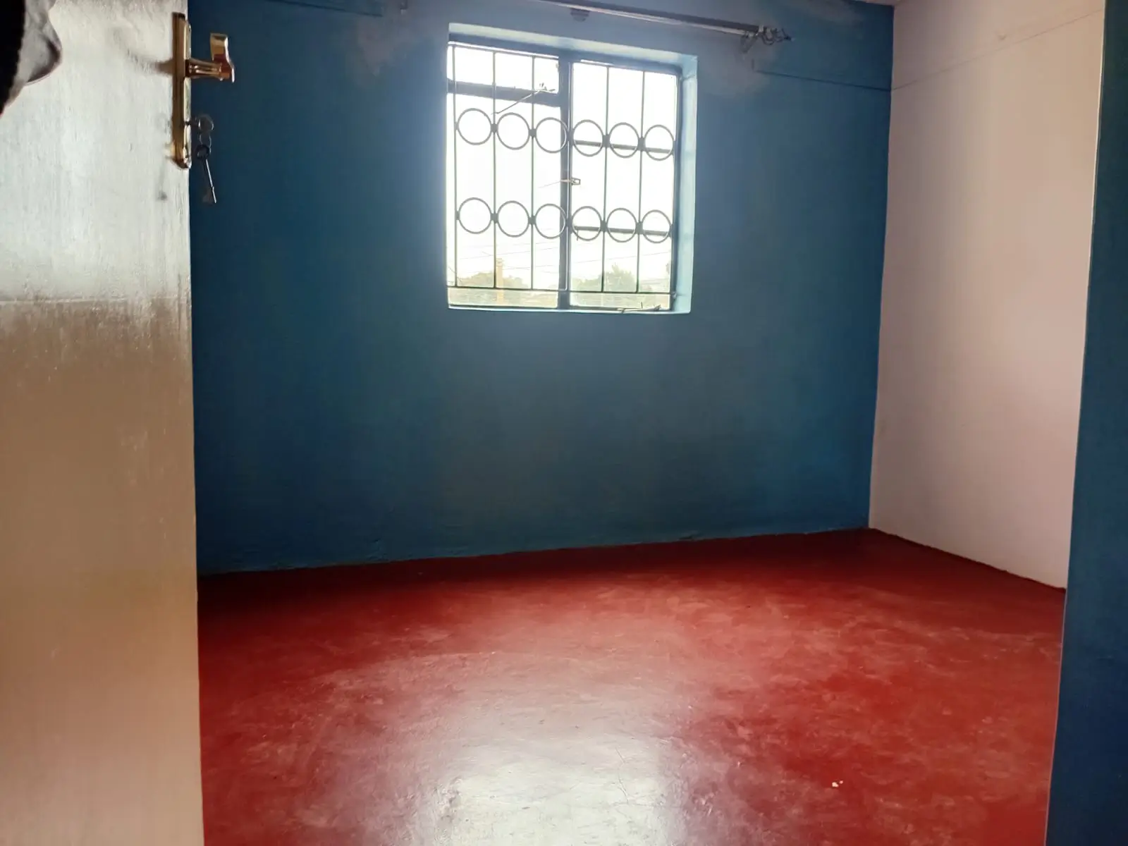 Empty bedroom with blue accent wall and red polished floor