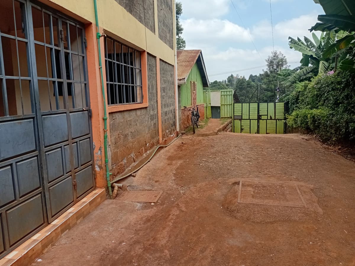 Compound driveway with metal gate and red soil surface