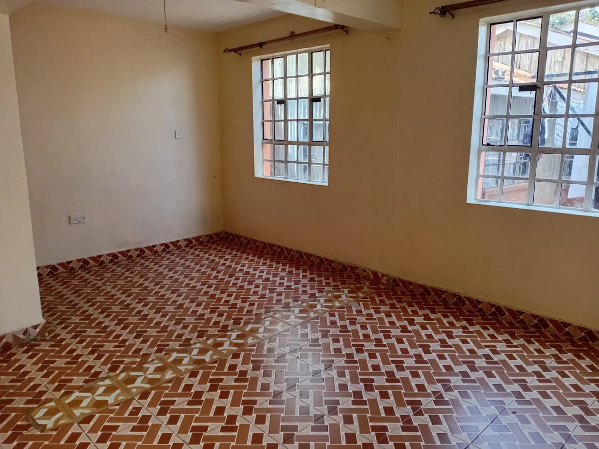 Empty living room with herringbone tile floor and windows