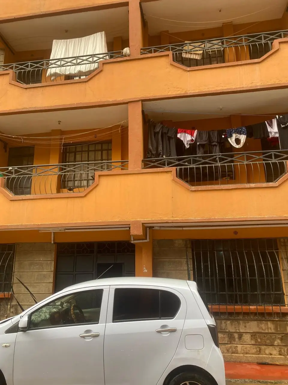 Orange apartment building facade with balconies and parked car