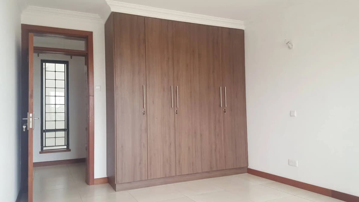 Spacious bedroom with large wooden wardrobe and entry door