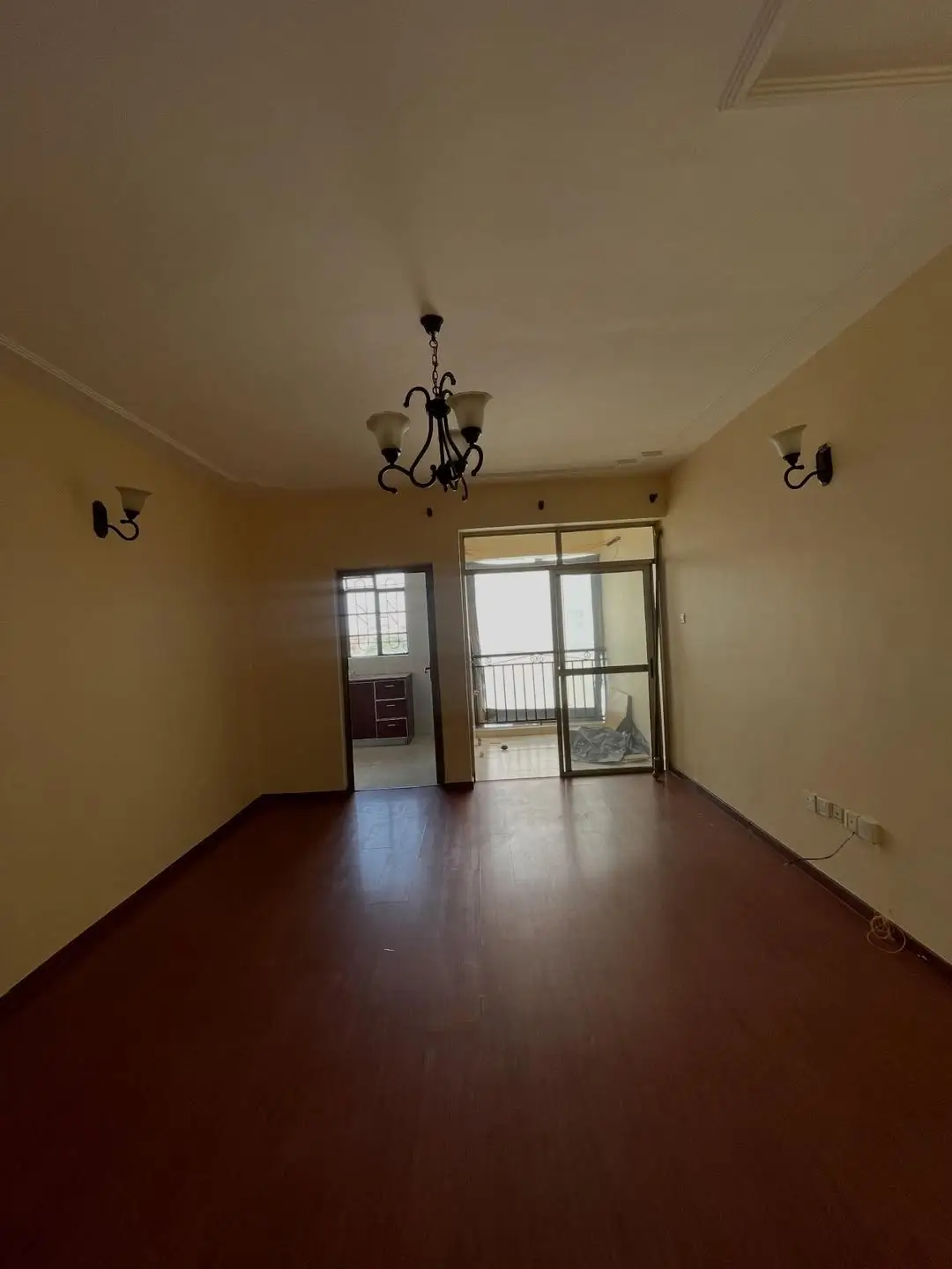Empty living room with yellow walls, dark wooden floor