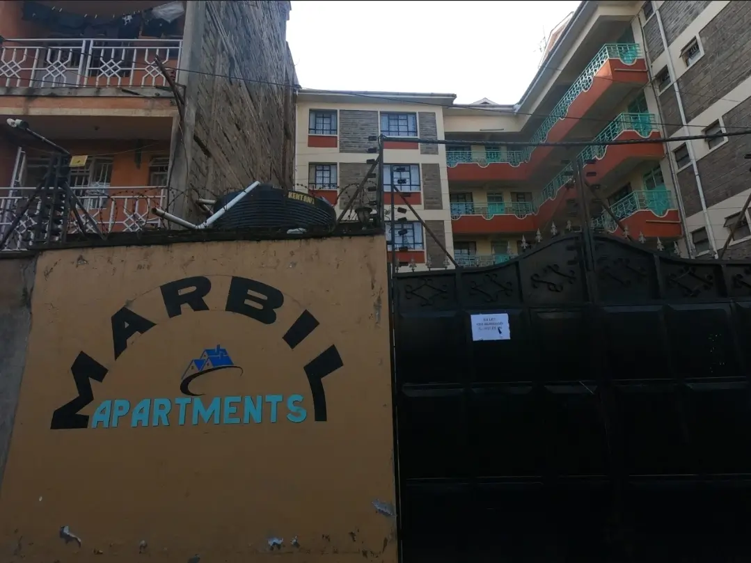 Multi-story apartment building with signage and compound entrance