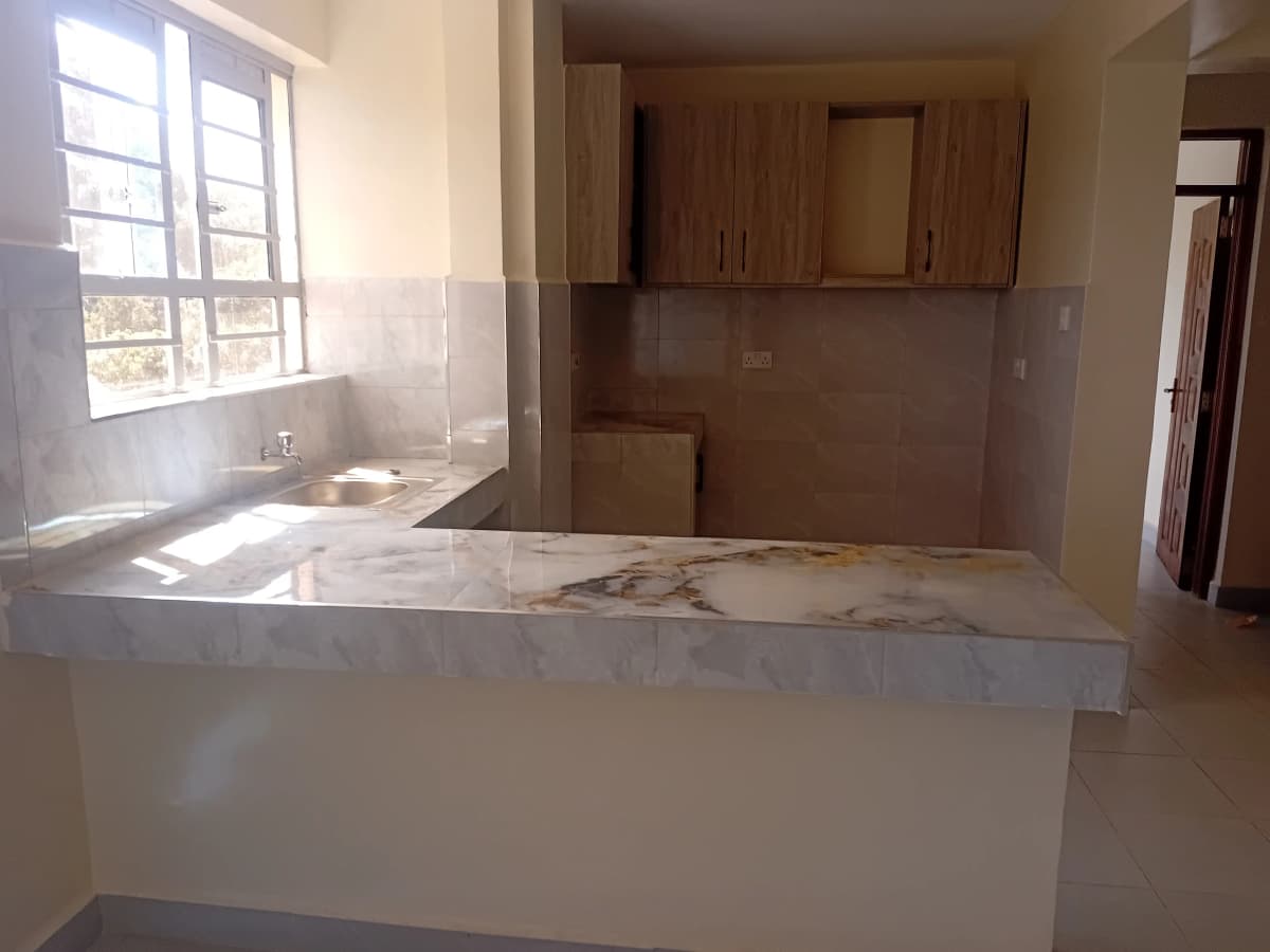 Open-plan kitchen with marble countertop and living area view
