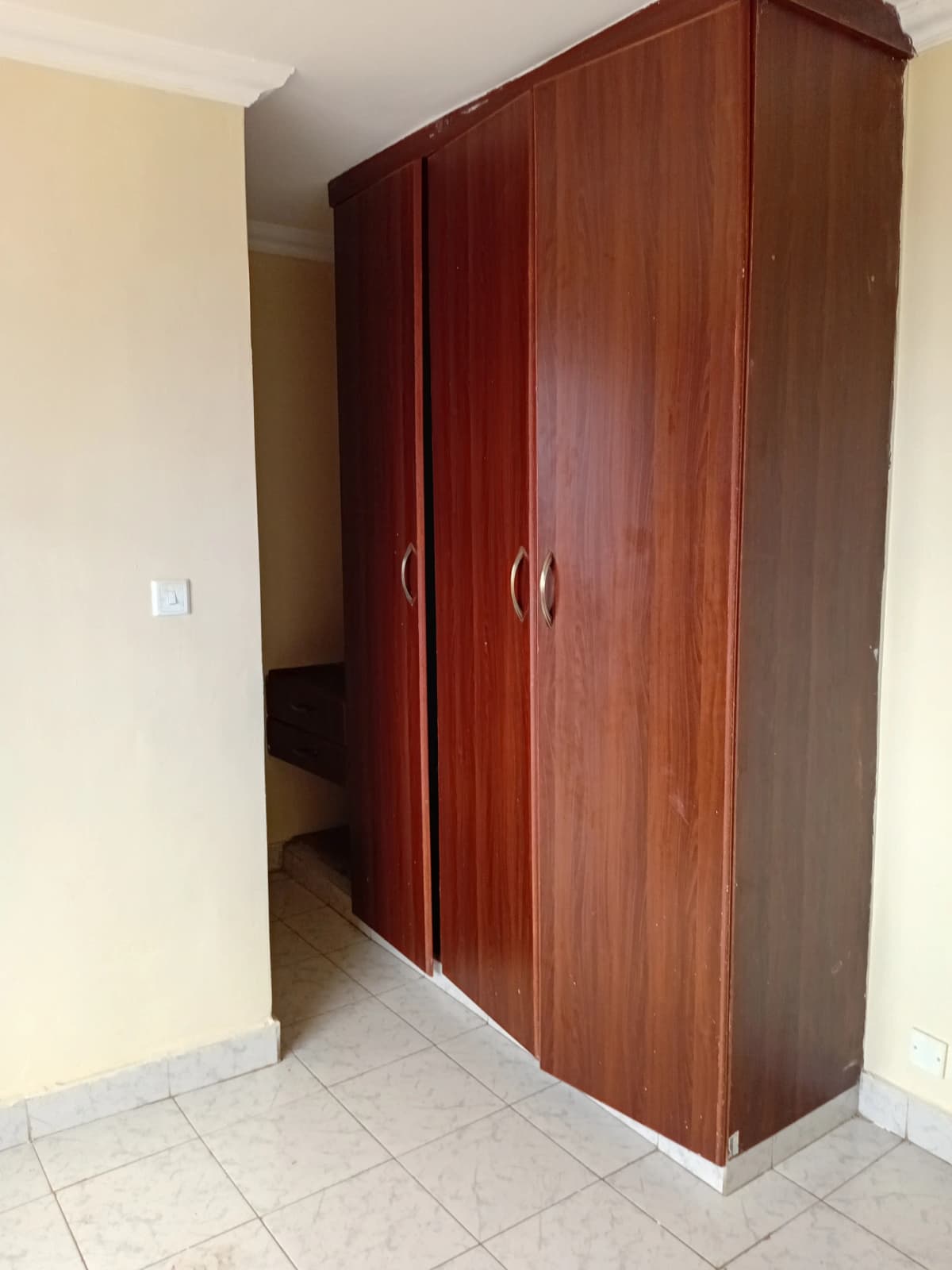 Bedroom with large wooden wardrobe and tile flooring