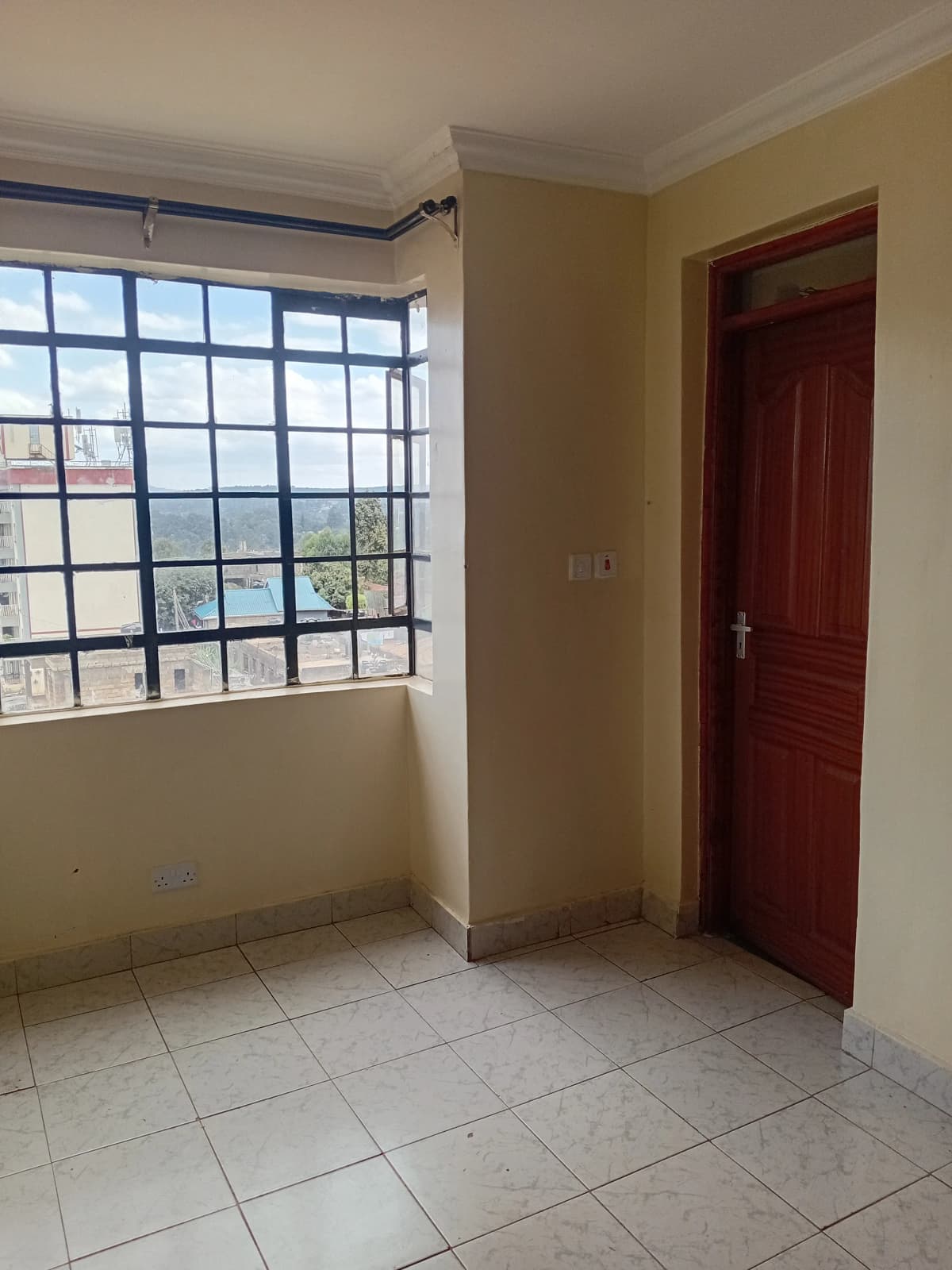 Bright bedroom with barred window and red door entry