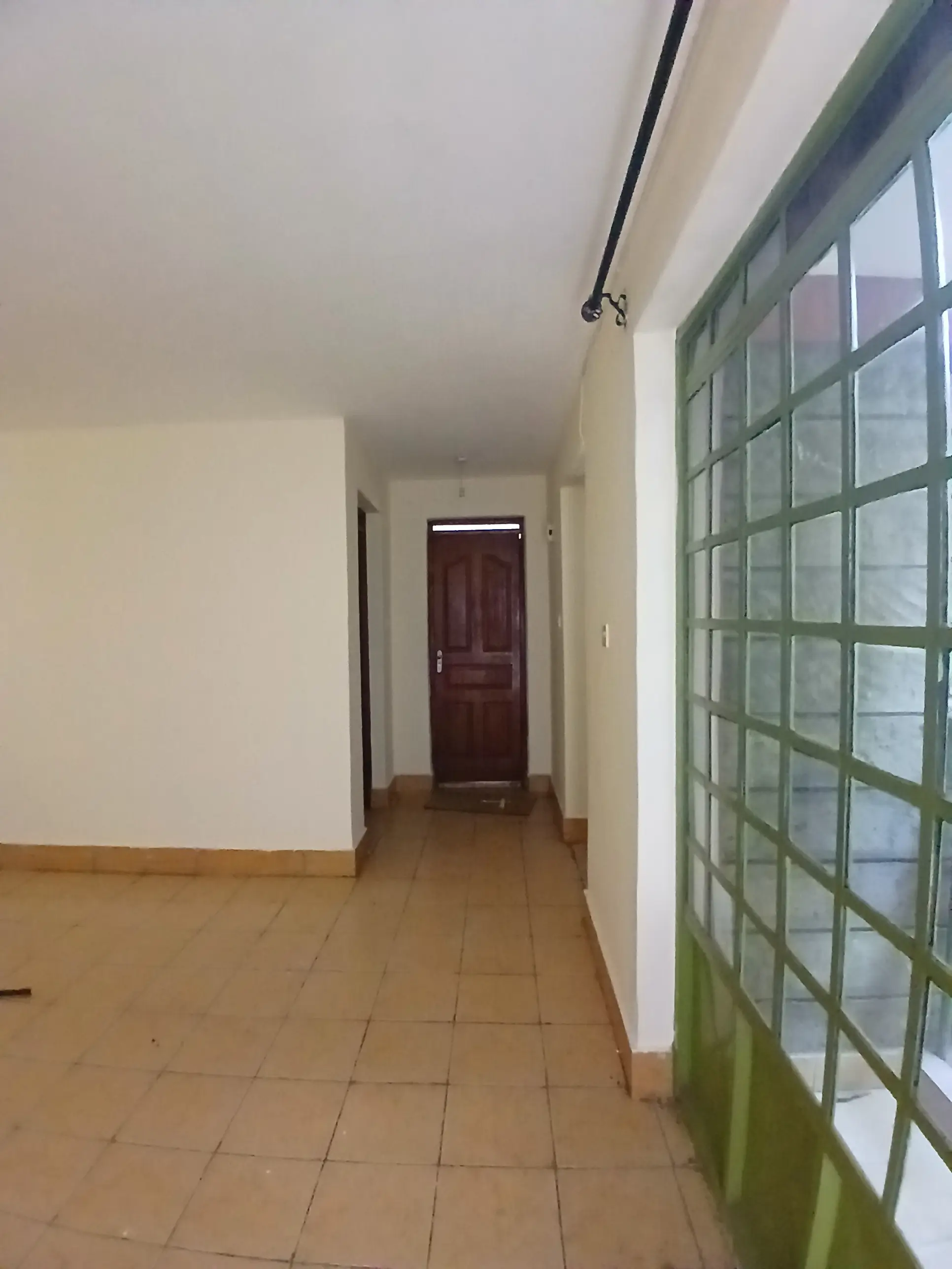 Hallway with tiled floor and green-framed window panels
