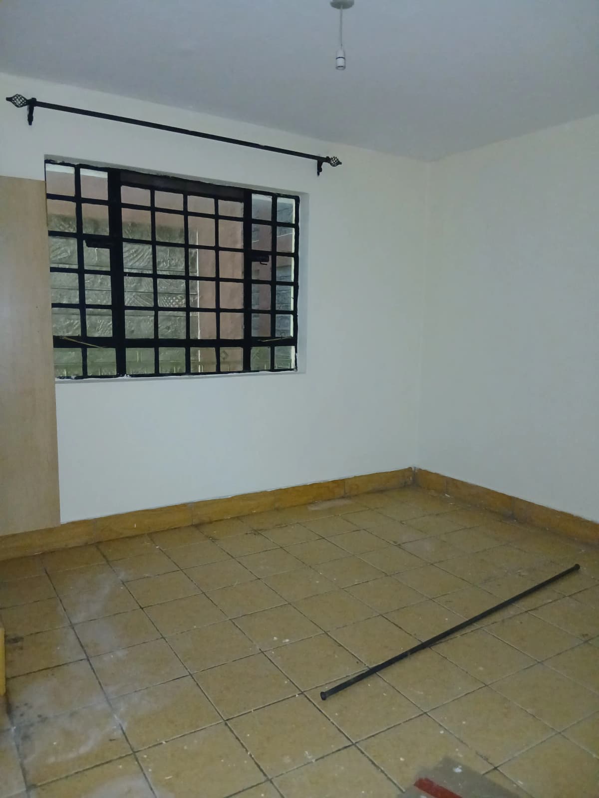 Sparse bedroom with barred window and tiled flooring