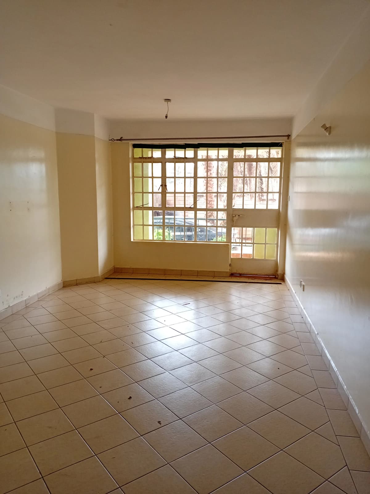 Spacious living room with large barred windows and tiled flooring