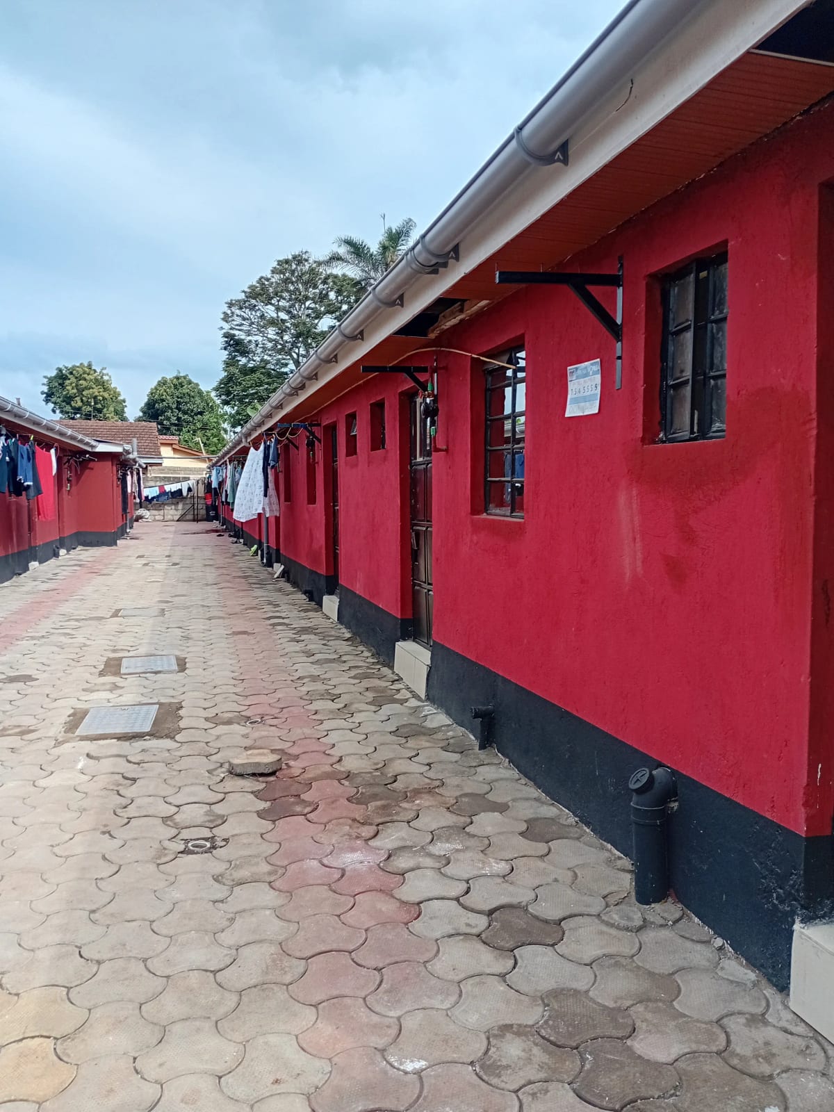 Red-painted residential units with paved courtyard entrance