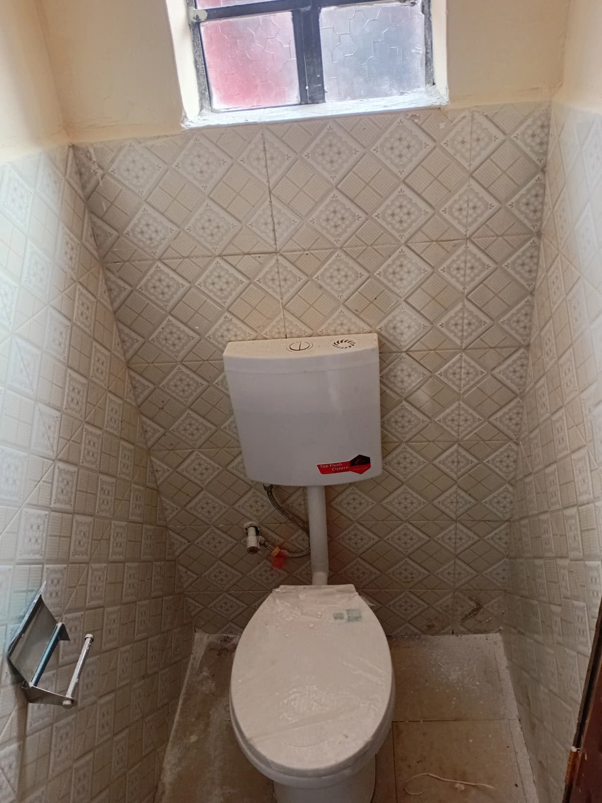 Compact toilet room with geometric tile walls and window