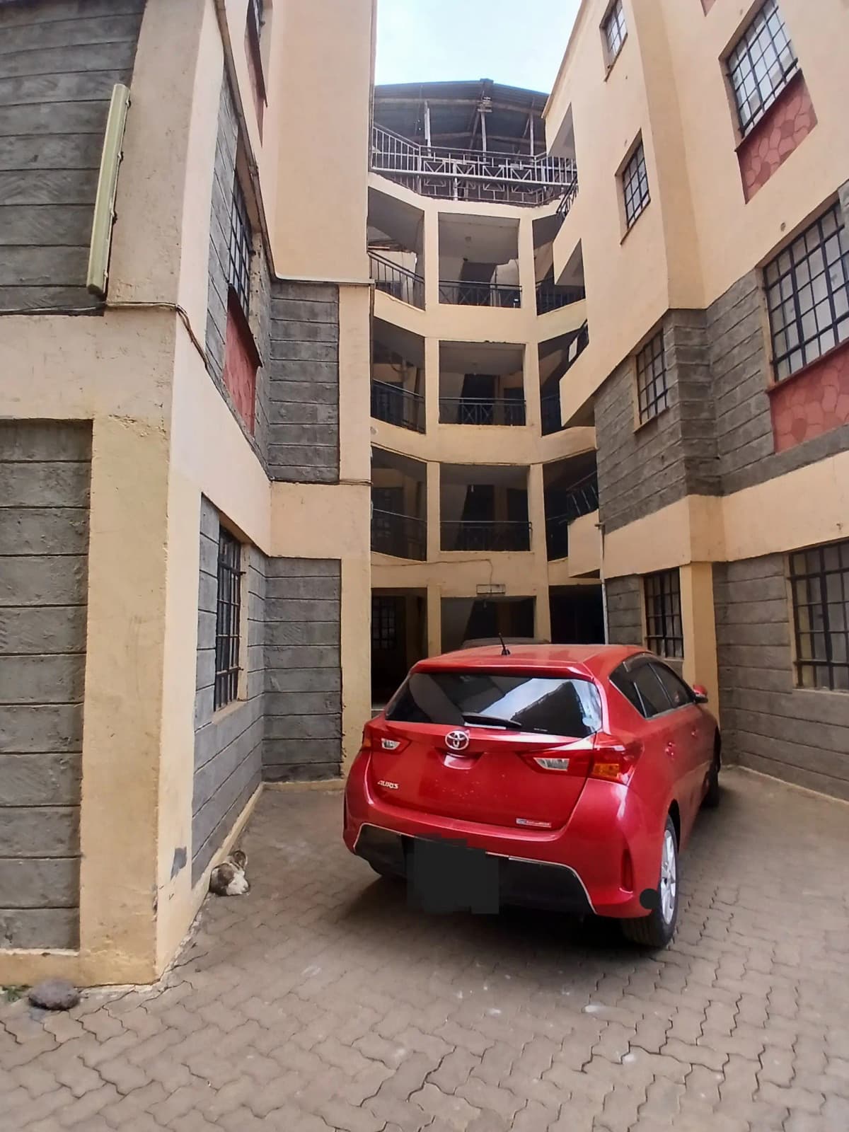 Residential compound parking bay with red vehicle parked
