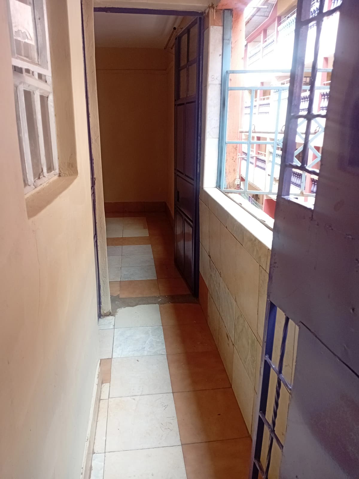Narrow corridor with terracotta tiles and street-facing windows