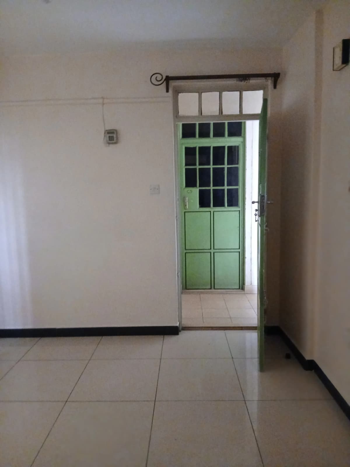 Building entrance lobby with green door and tiled flooring
