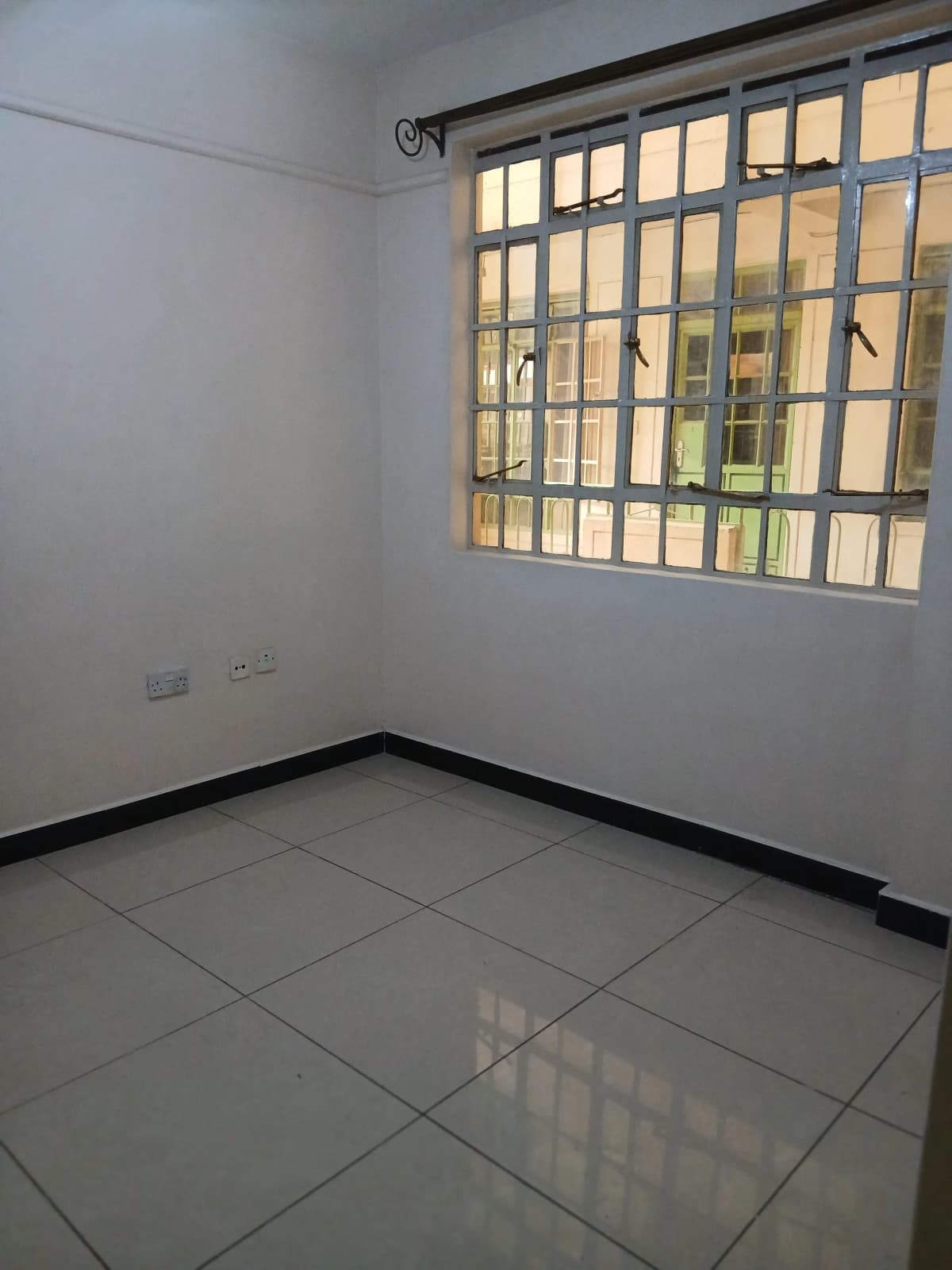 Unfurnished bedroom with tiled floor and barred window
