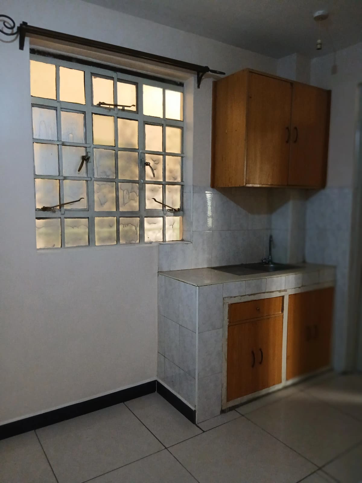 Compact kitchen with wooden cabinetry and tile countertop