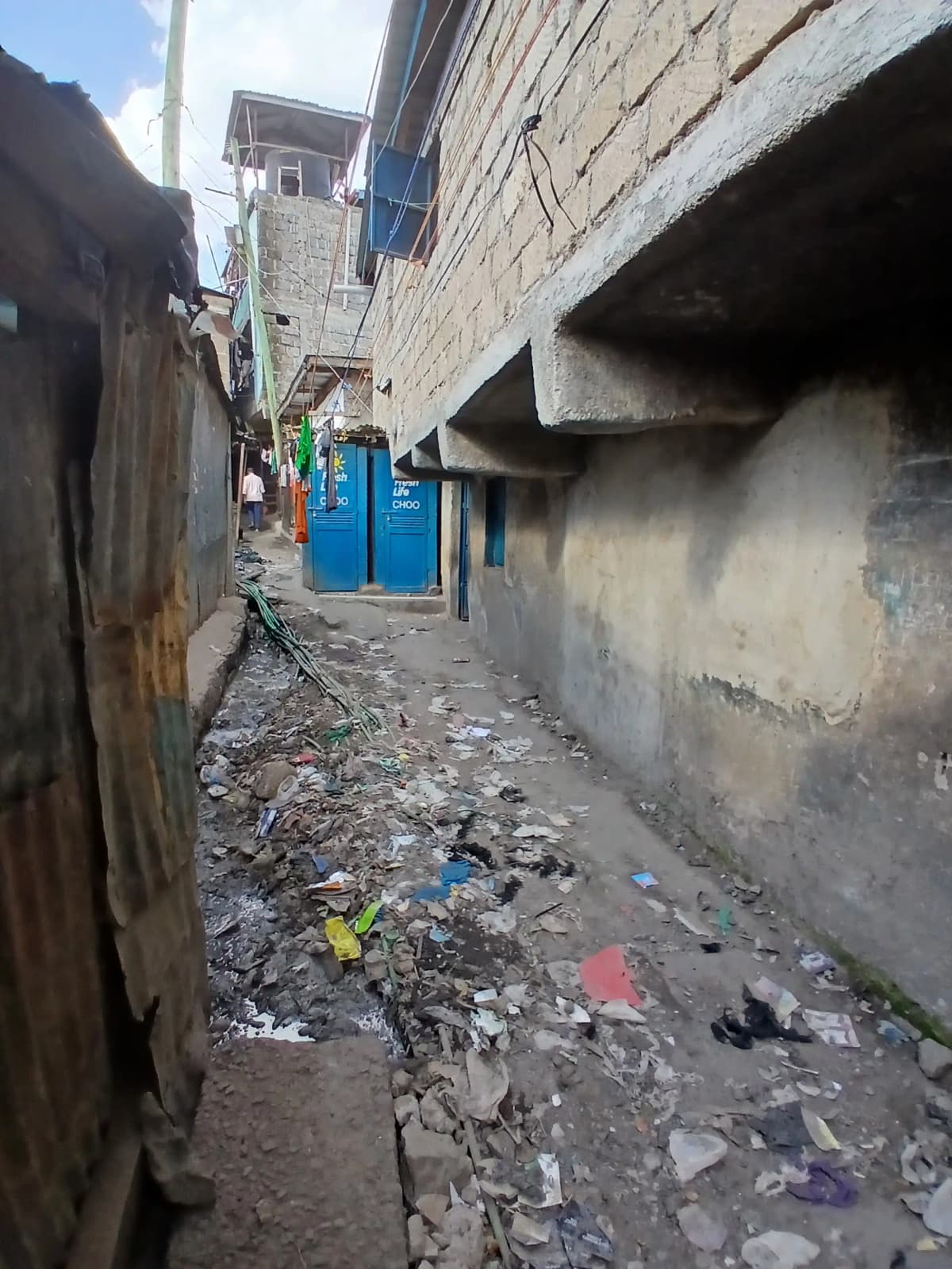 Narrow alleyway with blue gate and concrete structures