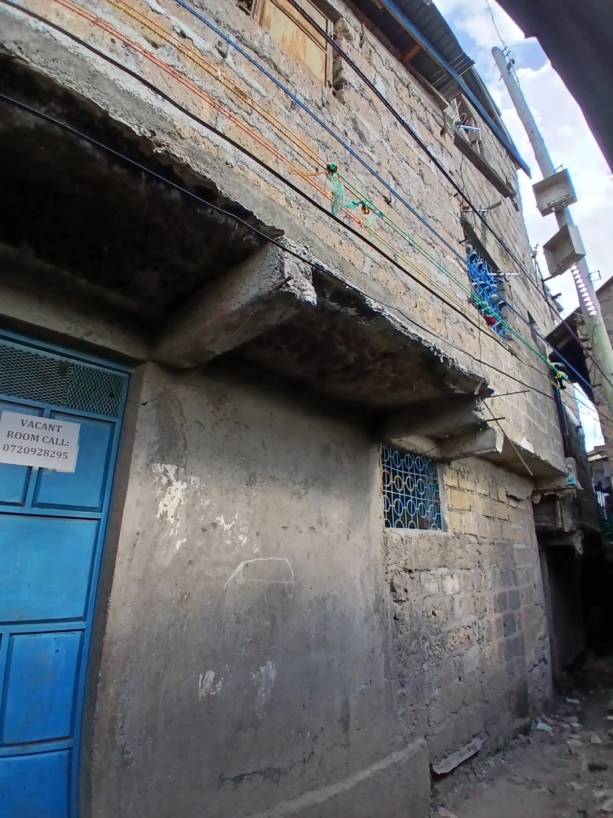 Weathered building facade with blue door and overhead structure