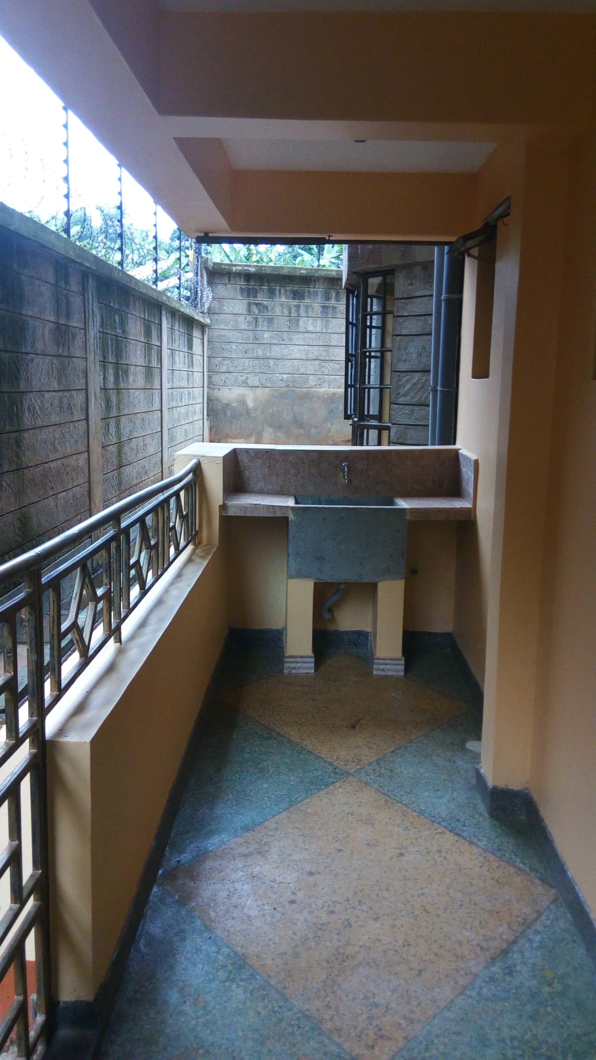 Narrow covered balcony with metal railing and concrete floor