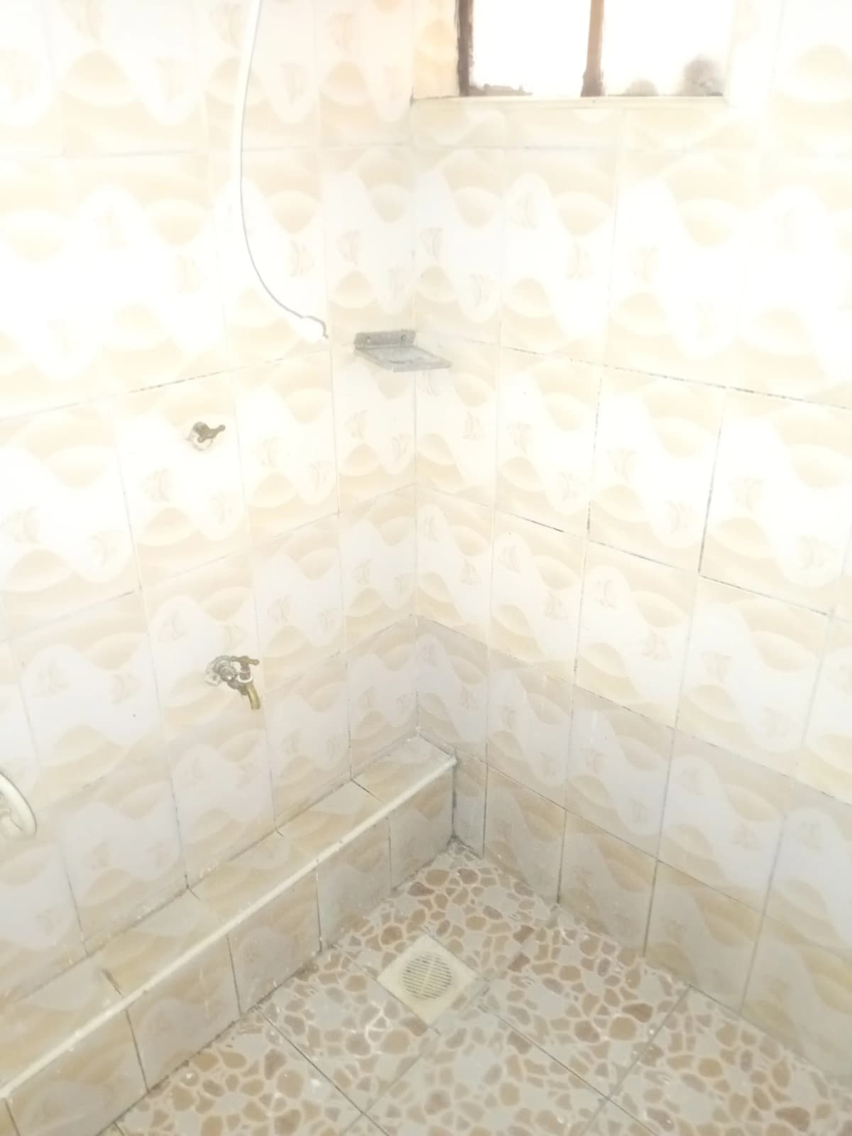 Compact bathroom with cream tiles and shower cubicle