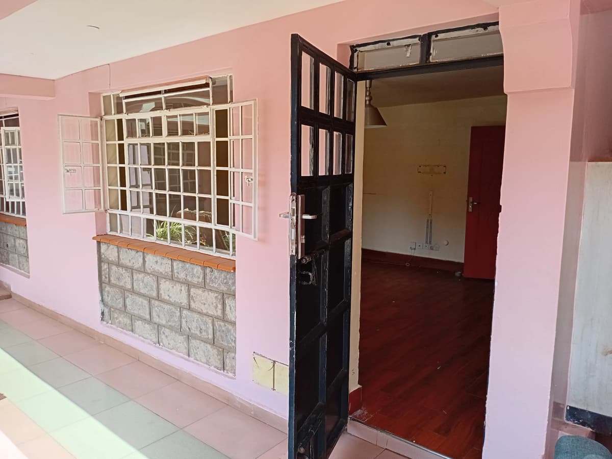Pink-walled corridor with black entrance door and security window