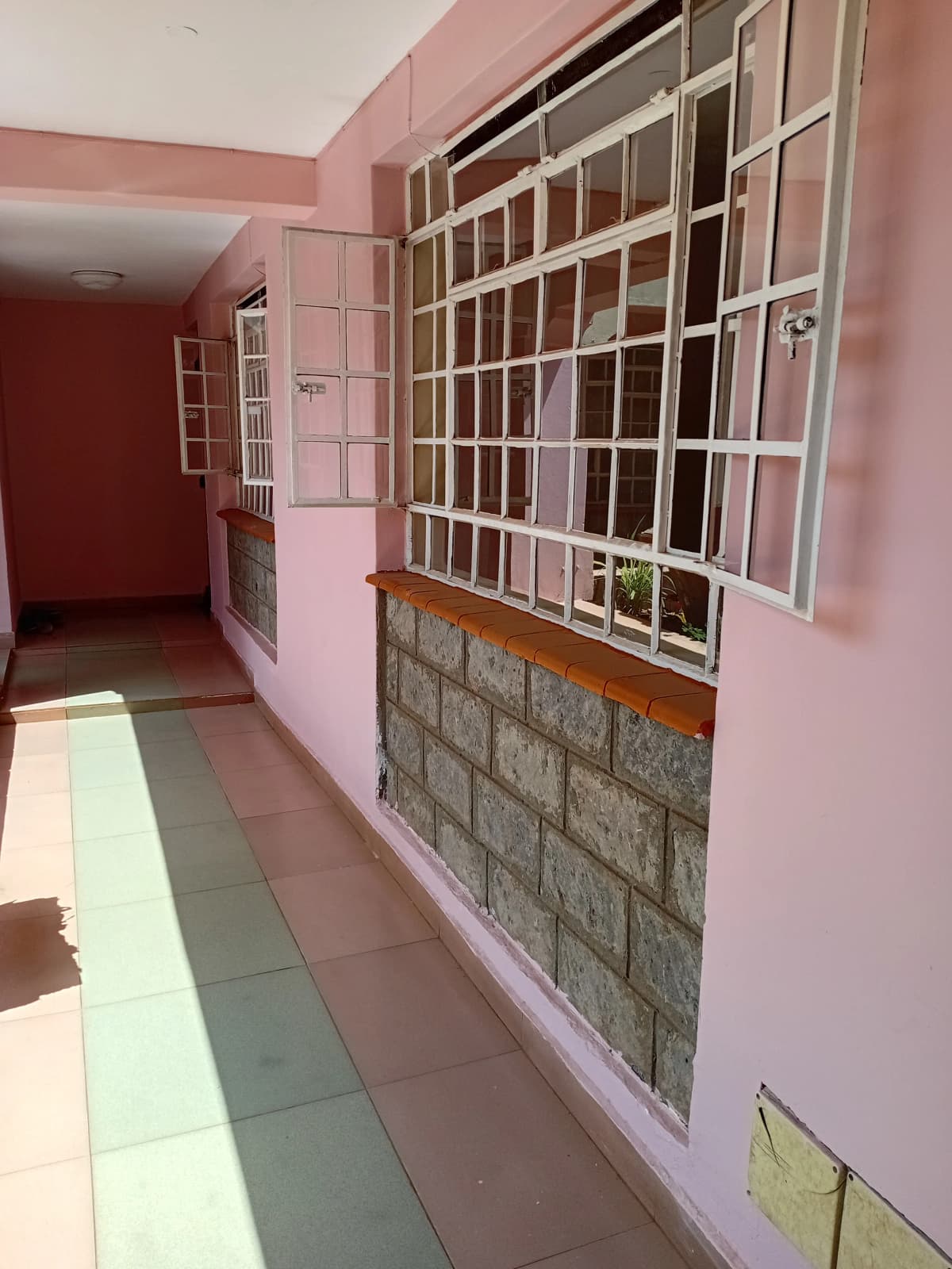 Pink-painted corridor with barred window and tiled flooring