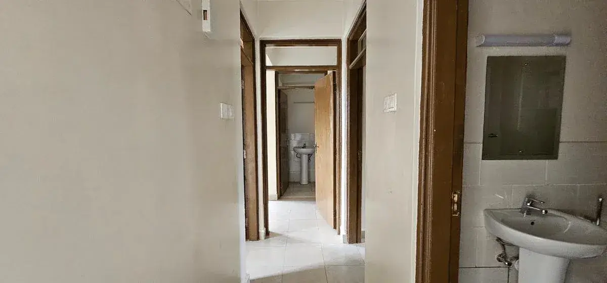 Hallway with bathroom entrance and sink visible right