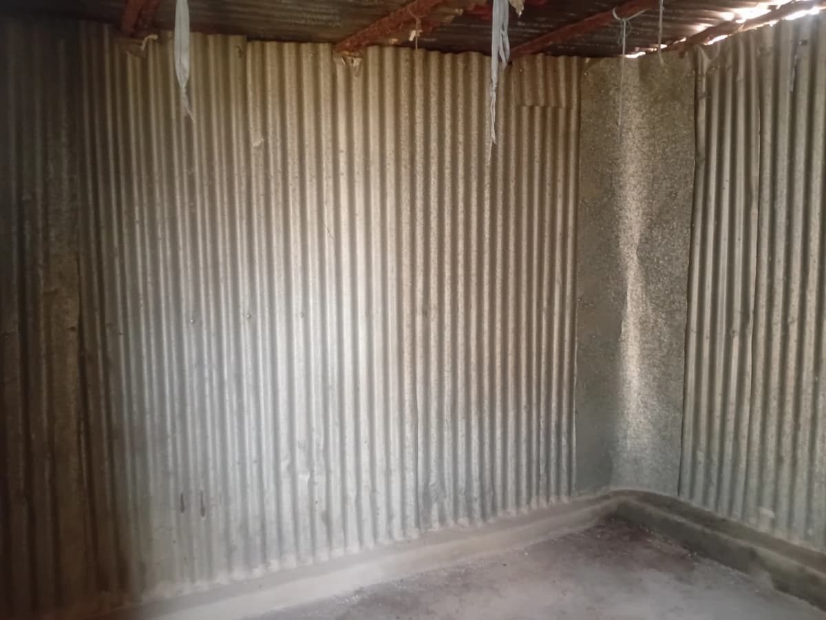 Empty room with corrugated metal walls, concrete floor