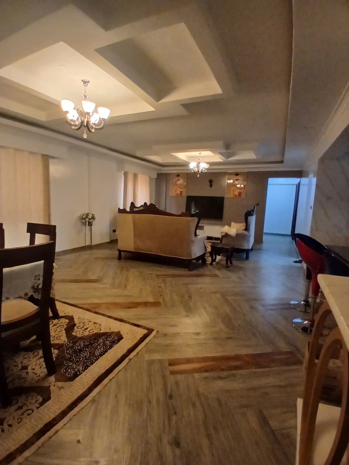 Spacious open-plan living area with coffered ceiling and chandelier
