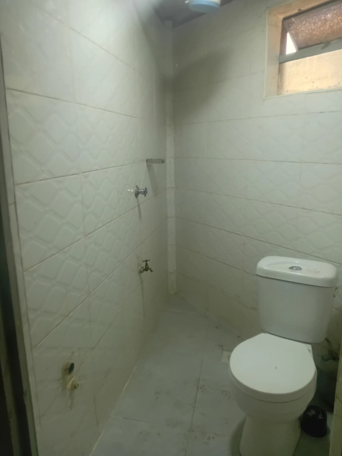 Compact bathroom with white tiles and basic fixtures